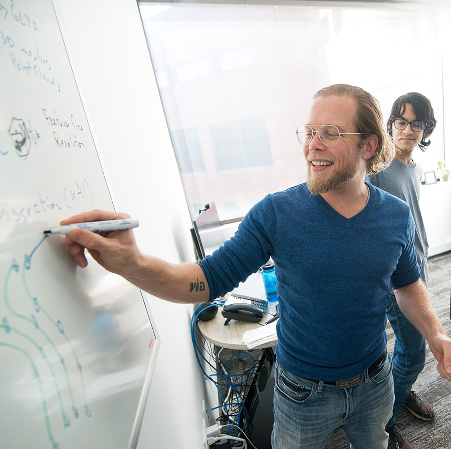 college of science instructor at whiteboard with students informal setting
