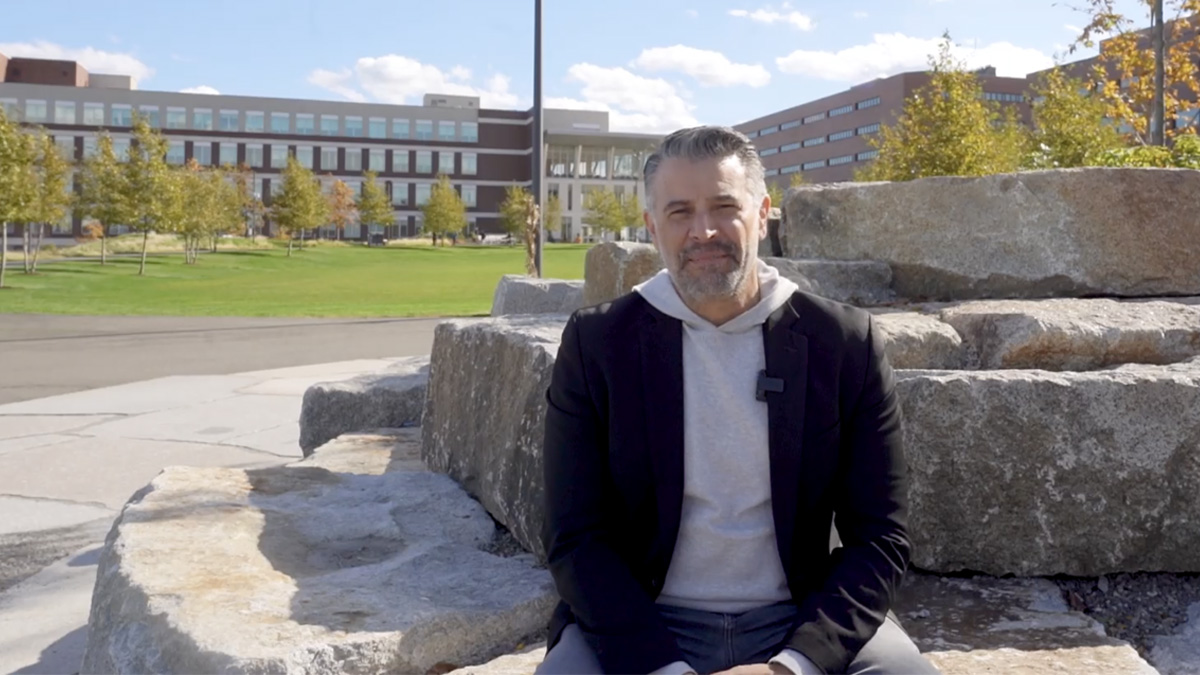 A professor sits on the UMass Boston quad