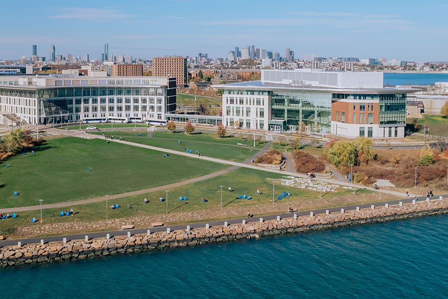 drone view of campus center lawn with Boston Skyline behind it.