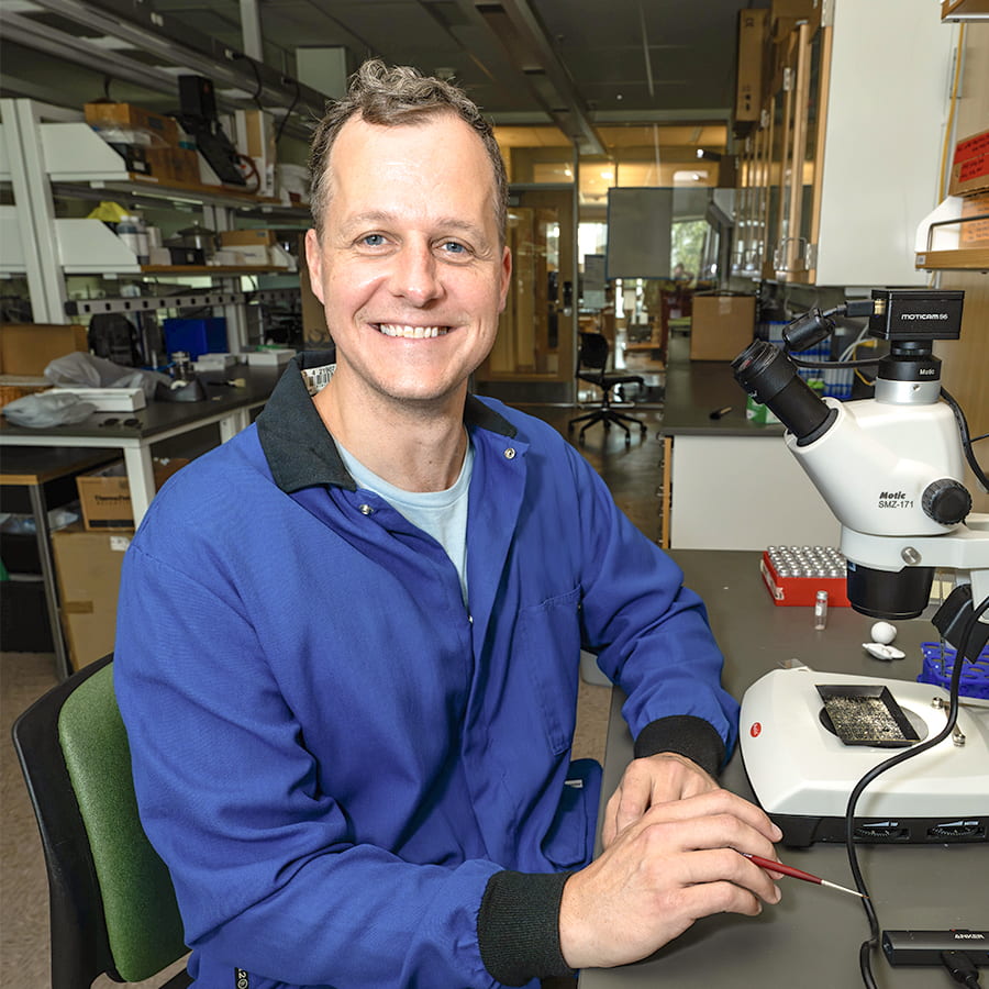 Jesse Farmer poses with microscope in lab.